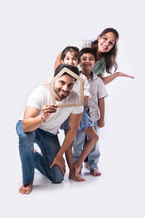 Indian family Father, mother, son and daughter holding 3D paper model of home - Real Istate Concept in Indiaの写真素材