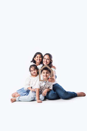 Indian family Father, mother, son and daughter holding 3D paper model of home - Real Istate Concept in Indiaの写真素材