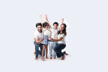 Indian family Father, mother, son and daughter holding 3D paper model of home - Real Istate Concept in Indiaの写真素材
