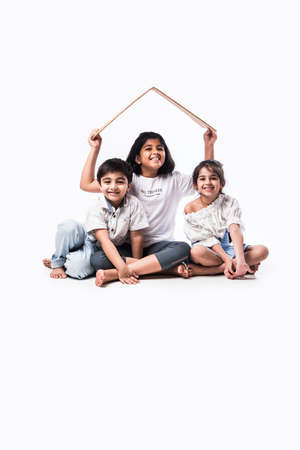 Indian kids holding 3D paper house model - showing Craft or real estate concept