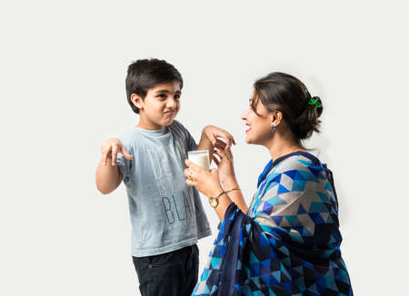 Indian pretty mother making her son drink milk in a glassの写真素材