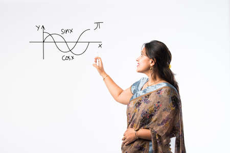 Portrait of Indian lady teacher in saree stands against green, white or blackboard , conducting...