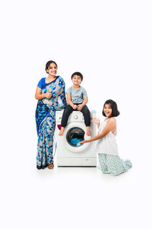 Indian Asian pretty Housewife washing cloths in washing machine and kids watchingの写真素材