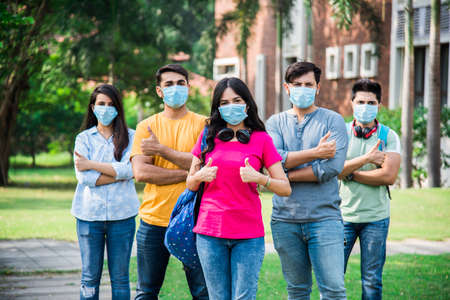 Asian Indian students wears face mask and follow social distancing norms in college or university campus after corona Pandemic unlock, focus on one studentの写真素材