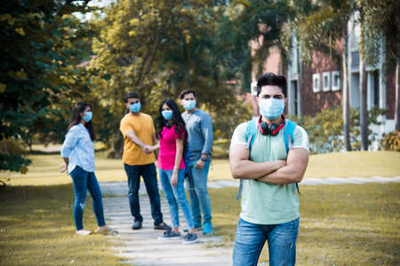 Asian Indian students wears face mask and follow social distancing norms in college or university campus after corona Pandemic unlock, focus on one studentの写真素材