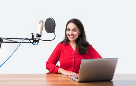 Pretty Indian woman speaks in front of microphone while recording a video blog for his subscribers,...