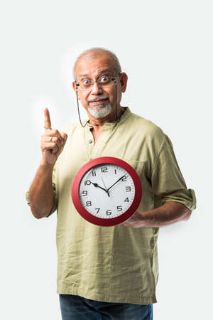 Senior Asian Indian man holding round wall clock - time management conceptの写真素材