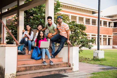 Cheerful Indian asian young group of college students or friends laughing together while sitting,...
