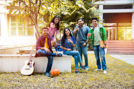 Asian Indian group of college students having tea of coffee together in break in campus premises...