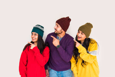 Indian asian young friends wears colourful and warm woollen sweaters and hats and pointing