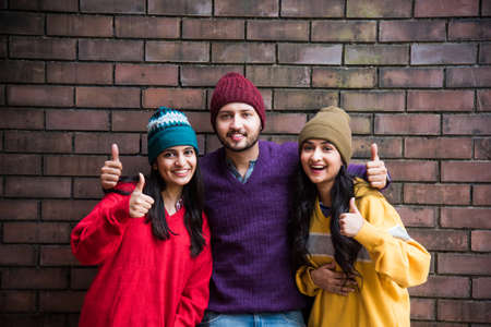 Indian asian young friends wears colourful and warm woollen sweaters and hats and pointing