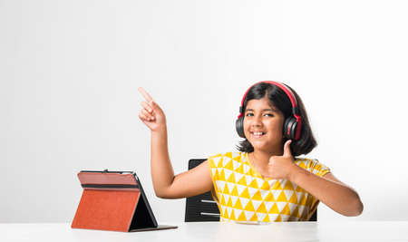 Pretty stylish Indian asian schoolgirl studying attending online lesson at home, social distance...