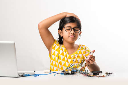 electronic experiment - Asian Indian small girl student performing or studying science with wires, connections, studying from laptop or tablet computerの写真素材