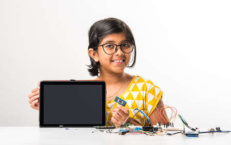 electronic experiment - Asian Indian small girl student performing or studying science with wires, connections, studying from laptop or tablet computerの写真素材