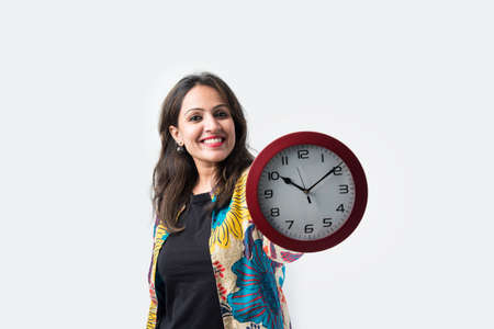 Pretty Asian Indian woman or young lady holding round wall clock - time management concept