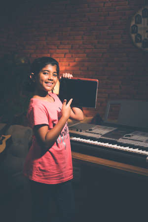 Asian Indian child learning music or musical instrument online using laptop computer or tablet at home, persuing hobbyの写真素材