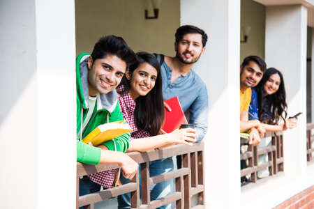 Cheerful Indian asian young group of college students or friends laughing together while sitting, standing or walking in campusの写真素材