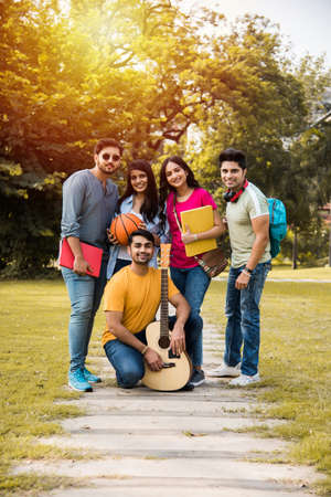 Cheerful Indian asian young group of college students or friends laughing together while sitting,...
