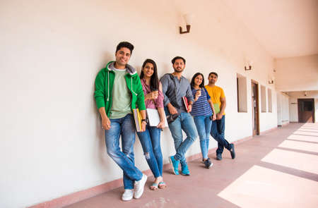 Cheerful Indian asian young group of college students or friends laughing together while sitting,...