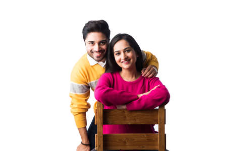 Asian Indian couple wears colourful warm sweater or woolen winter cloths, standing isolated against white backgroundの写真素材