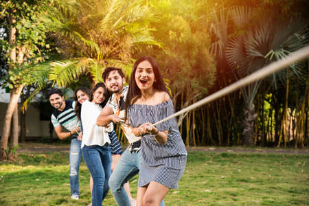 Team of Indian asian young friends Team playing or competing in tug of war or rassi khech