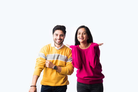 Asian Indian couple wears colourful warm sweater or woolen winter cloths, standing isolated against...