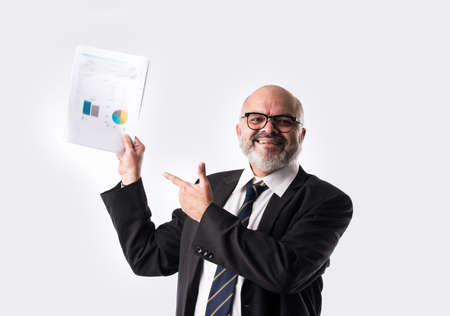 Portrait of Indian asian senior businessman holding or reading paper documents while standing against white backgroundの写真素材