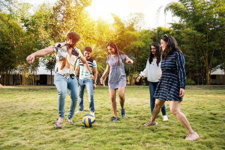 Indian asian young friends playing soccer or football in park and having fun