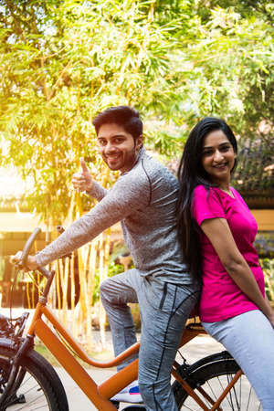 Portrait of happy Indian Asian couple riding a bicycle and smilingの写真素材