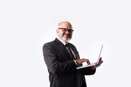 Portrait of Senior Indian asian businessman using laptop, tablet or smartphone while standing against white background, showing or presentingの写真素材