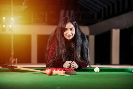 A group of young Indian asian young people or friends playing fun billiards, snooker or pool