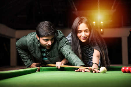 A group of young Indian asian young people or friends playing fun billiards, snooker or poolの写真素材