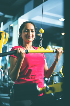 Attractive young Indian asian woman working out in the gym - health and fitness concept