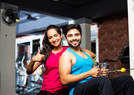 Indian asian Young couple is working out in the gym. Attractive woman and handsome fit man are...