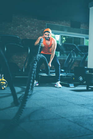 Handsome Indian asian young man doing battle rope exercise while working out in gym, selective focusの写真素材
