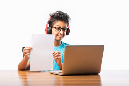 Indian male student or kid studying online using laptop. Asian child attending online school using...