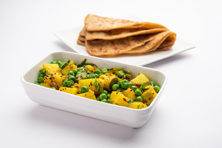 Aloo Mutter or Matar aalu dry sabzi, Indian Potato and green Peas fried together with spices and garnished with coriander leaves. served with roti or chapatiの写真素材