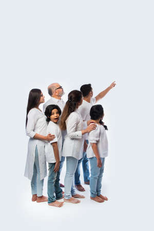 Indian multigenerational family pointing or presenting empty space, standing isolated against white backgroundの写真素材