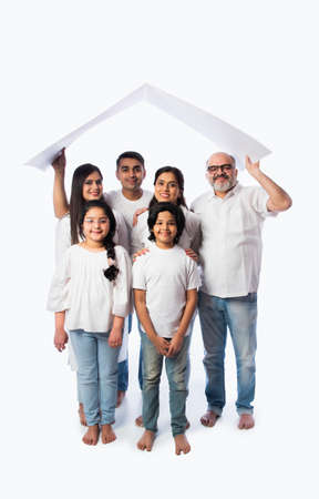 Indian family and real estate concept - Multigenerational asian family holding paper house model with keys against white backgroundの写真素材