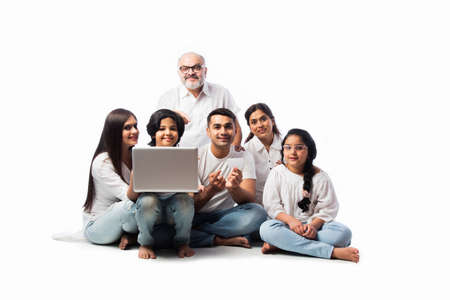 Multigenerational Indian asian family of six online shopping using laptop and electronic card while...