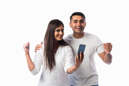 Indian asian young couple using smartphone against white backgroundの写真素材