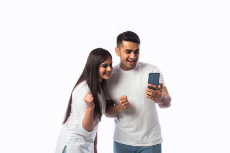 Indian asian young couple using smartphone against white backgroundの写真素材
