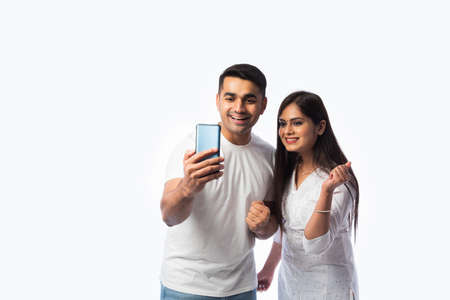 Indian asian young couple using smartphone against white background