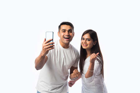 Indian asian young couple using smartphone against white background