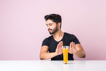 Portrait of a handsome Indian young man drinking orange juice in kitchen in the morning