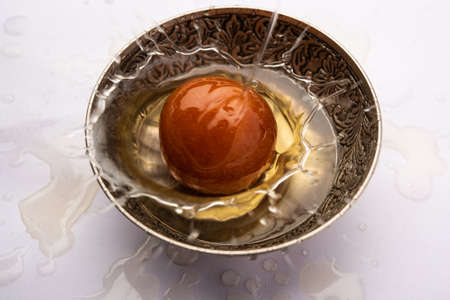 Indian sweet Gulab Jamun falling in bowl making syrap splash , single pieceの写真素材