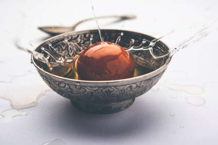 Indian sweet Gulab Jamun falling in bowl making syrap splash , single pieceの写真素材