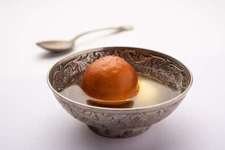 Indian sweet Gulab Jamun falling in bowl making syrap splash , single pieceの写真素材