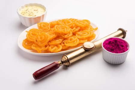 Happy Holi greeting card - Sweet Jalebi, Jilapi, zulbia, mushabak or zalabia with Thandai drink and gulal colour arranged over white backgroundの写真素材