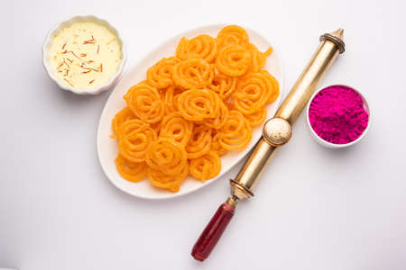 Happy Holi greeting card - Sweet Jalebi, Jilapi, zulbia, mushabak or zalabia with Thandai drink and gulal colour arranged over white backgroundの写真素材